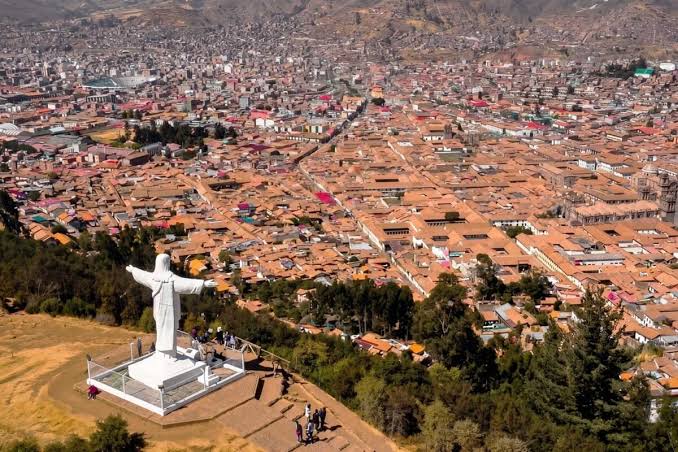 Cusco terracotta rooftops elevated view from hillside, Andes mountains in background, Peru destination overview