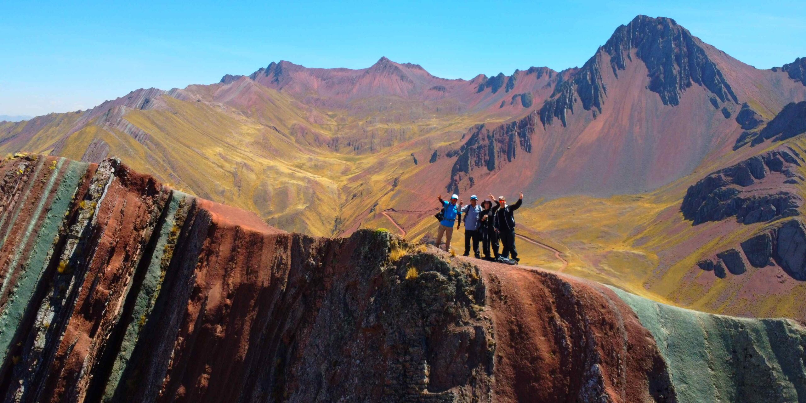 Sharp, striped ridgelines of Pallay Punchu with alpacas grazing on the surrounding Andean grassland