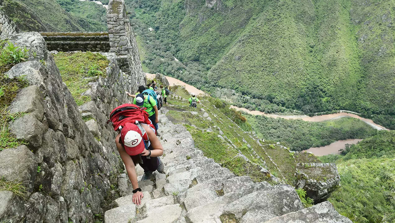 Steep Inca stone stairway on the Huayna Picchu ascent, with Machu Picchu visible far below