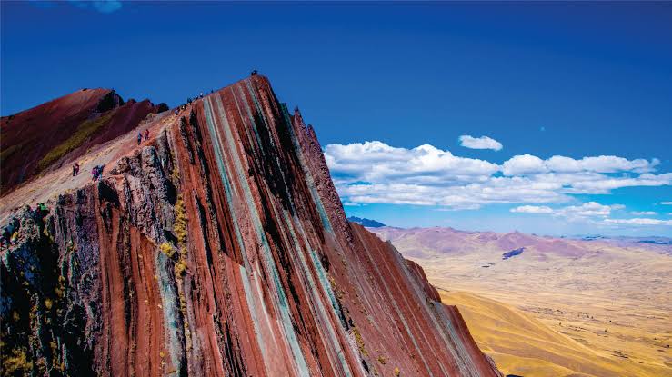 Jagged, multicolored ridges of Pallay Punchu rainbow mountain above Laguna Langui, Cusco region, Peru